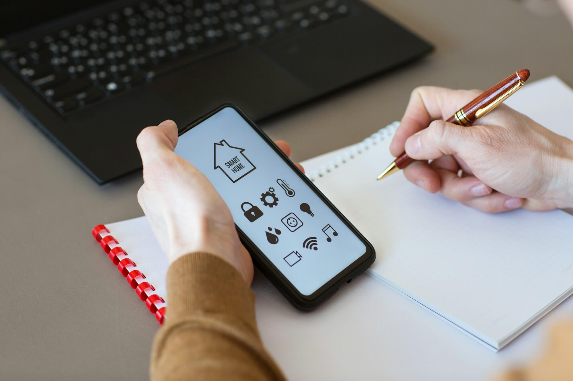 man-controls-smart-home-devices-using-app-for-mobile-phone-on-background-of-businessman-s-work-table.jpg